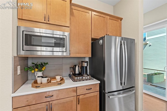 48 Mayflower Park Pl, Colorado Springs, CO 80905 - kitchen with appliances with stainless steel finishes, light countertops, decorative backsplash, and light wood finished floors