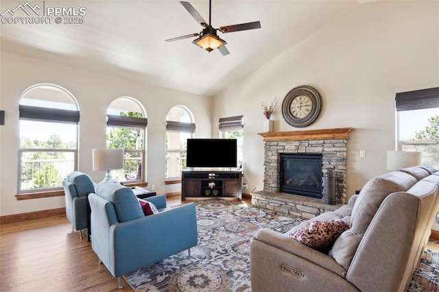 living area with plenty of natural light, a stone fireplace, wood finished floors, and ceiling fan