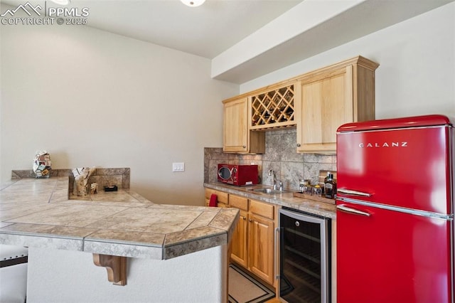 bar with a sink, beverage cooler, indoor wet bar, backsplash, and freestanding refrigerator