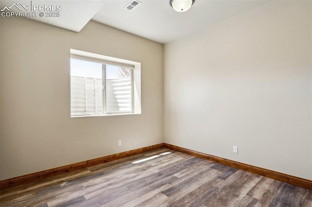 spare room featuring baseboards, wood finished floors, and visible vents