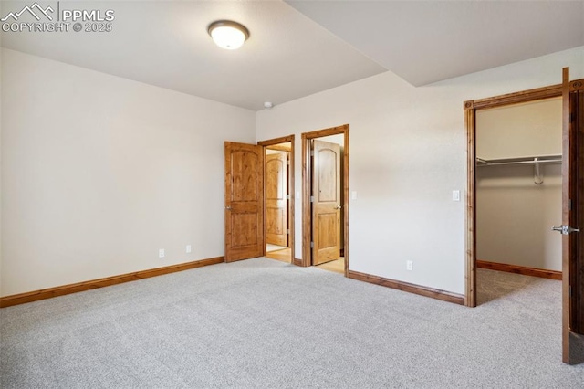 unfurnished bedroom with a walk in closet, baseboards, carpet floors, and a closet