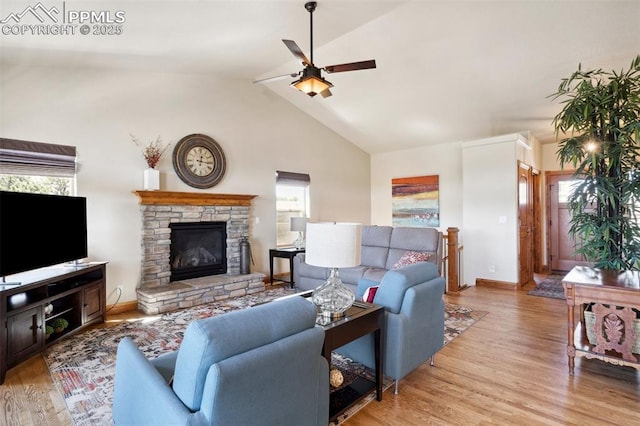 living room with wood finished floors, a ceiling fan, baseboards, and a stone fireplace