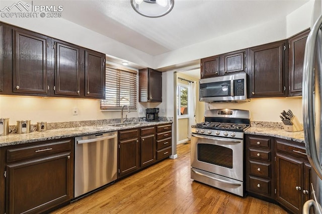 620 Jayton Dr, Colorado Springs, CO 80911 - kitchen featuring dark brown cabinets, light wood finished floors, stainless steel appliances, and a sink