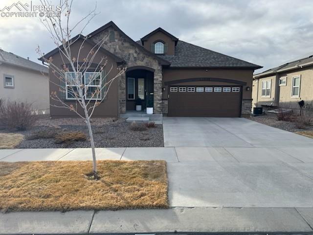 10088 Stonemont Dr, Peyton, CO 80831 - view of front of property with a garage, driveway, stone siding, and stucco siding