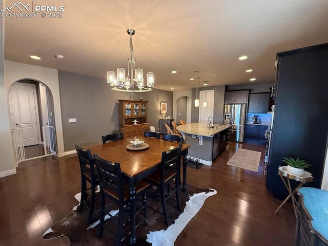 10088 Stonemont Dr, Peyton, CO 80831 - dining area featuring arched walkways, dark wood-style flooring, an inviting chandelier, and recessed lighting