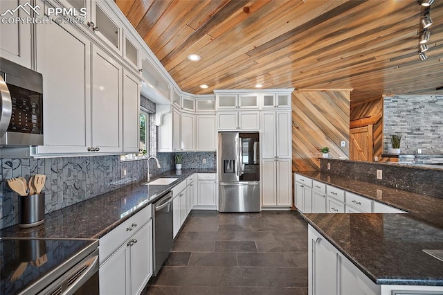 kitchen with white cabinets, stainless steel appliances, dark stone countertops, wooden ceiling, and a sink
