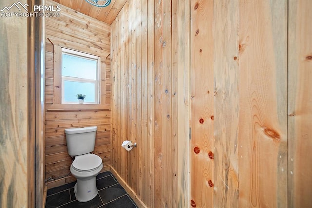 bathroom featuring tile patterned flooring, wood walls, wood ceiling, and toilet