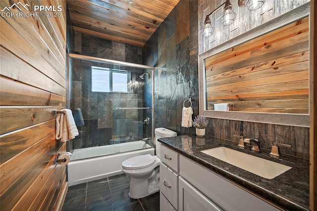 full bath featuring tile patterned floors, bath / shower combo with glass door, toilet, wooden walls, and vanity