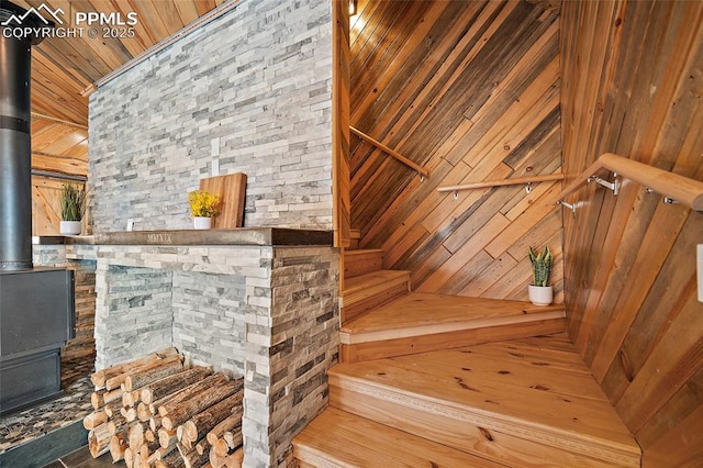 stairs with wooden ceiling, a wood stove, and wooden walls
