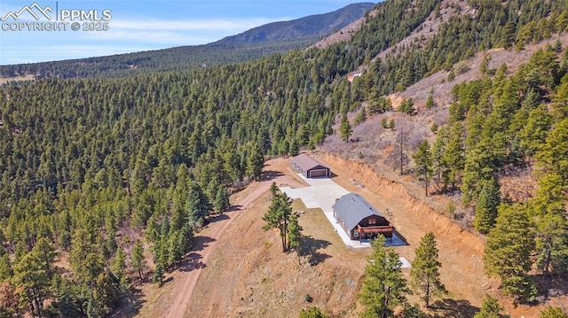 drone / aerial view with a wooded view and a mountain view
