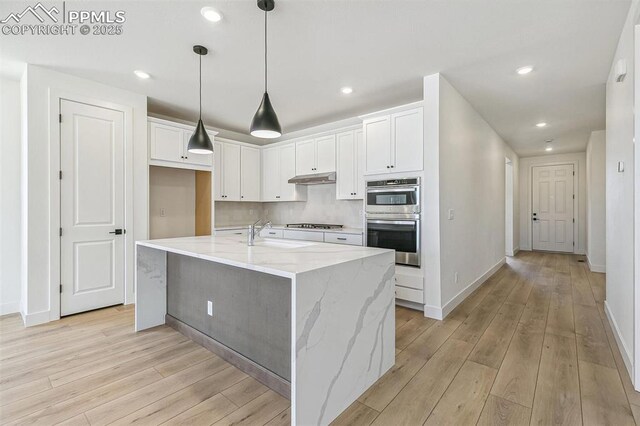 4331 Soapberry Pl, Castle Rock, CO 80108 - kitchen with white cabinetry, double oven, light wood finished floors, and under cabinet range hood
