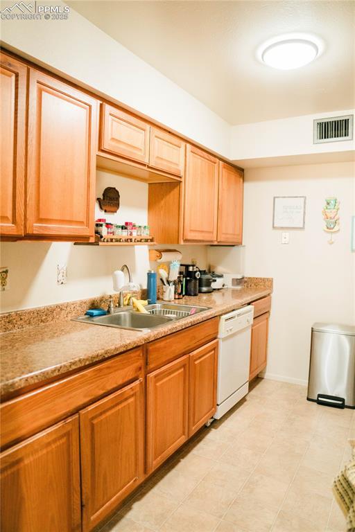 kitchen featuring visible vents, baseboards, dishwasher, a sink, and light countertops