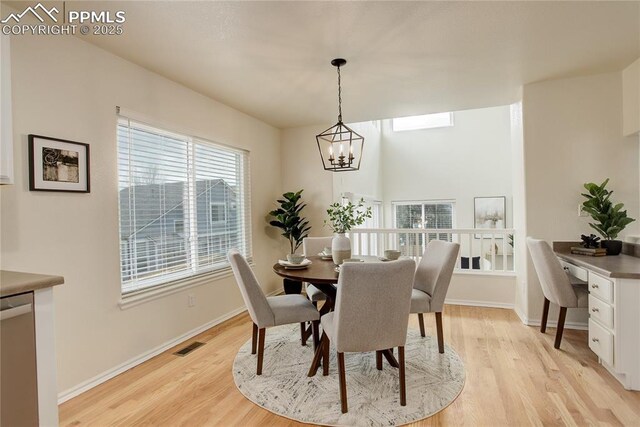 dining space featuring light wood-style flooring, visible vents, baseboards, and a notable chandelier