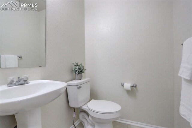 bathroom with toilet, baseboards, and a sink