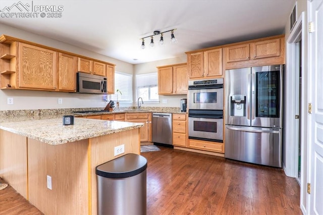 kitchen featuring stainless steel appliances, a peninsula, a sink, dark wood-style flooring, and open shelves