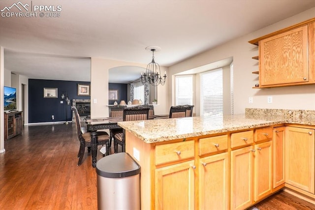kitchen with open shelves, an inviting chandelier, a peninsula, light stone countertops, and dark wood-type flooring