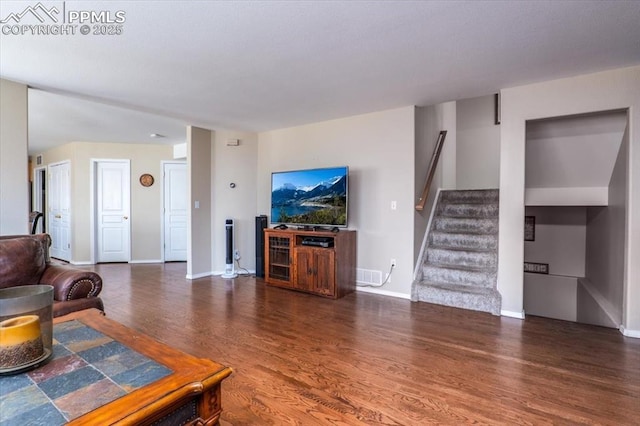 living area featuring baseboards, wood finished floors, and stairway