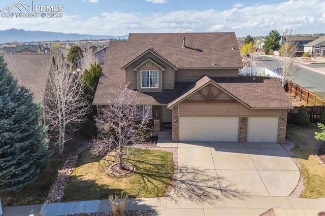 traditional-style home with an attached garage, driveway, a shingled roof, and fence