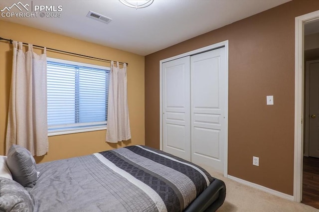 bedroom with baseboards, visible vents, carpet floors, and a closet
