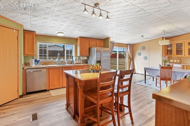 kitchen featuring light wood finished floors, light countertops, visible vents, a kitchen island, and appliances with stainless steel finishes
