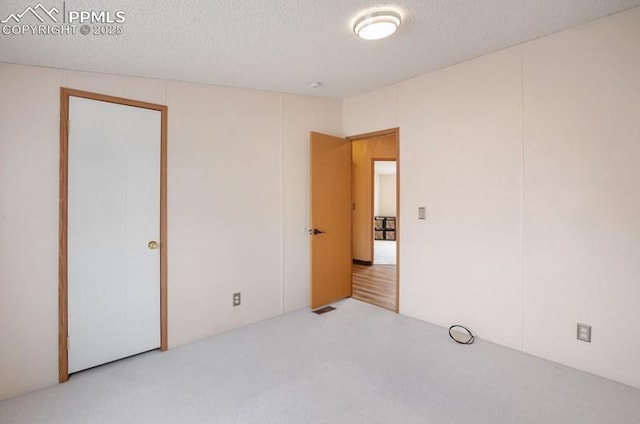 unfurnished bedroom featuring a textured ceiling, carpet, and visible vents