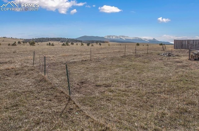 view of yard featuring fence, a rural view, and a mountain view