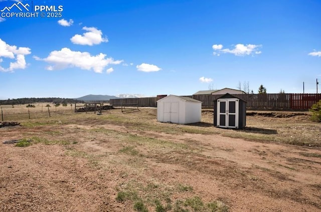 view of yard with fence, an outbuilding, a mountain view, and a shed