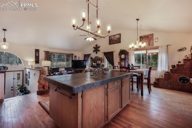 kitchen with hardwood / wood-style flooring, pendant lighting, a kitchen island, tile counters, and high vaulted ceiling