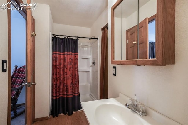 bathroom with curtained shower, wood finished floors, and a sink