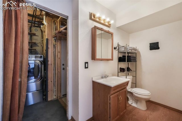 bathroom featuring washer / dryer, toilet, vanity, and wood finished floors