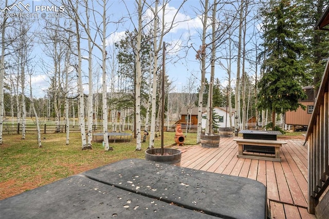 deck with fence, a lawn, and a trampoline