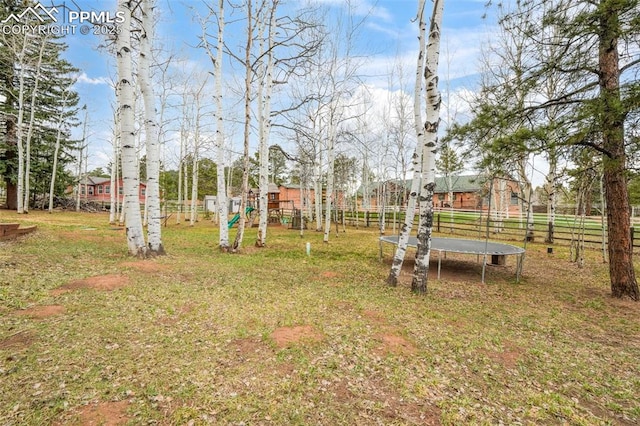 view of yard with fence, a playground, and a trampoline