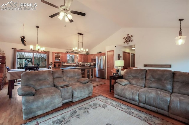 living area featuring light wood-type flooring, high vaulted ceiling, and ceiling fan with notable chandelier