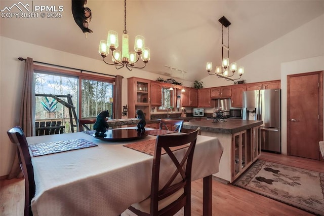 dining area with high vaulted ceiling, a notable chandelier, and light wood finished floors