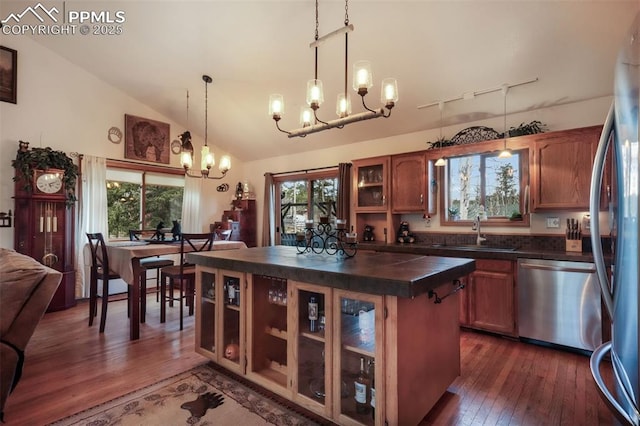kitchen with stainless steel appliances, dark wood-style floors, a sink, dark countertops, and an inviting chandelier