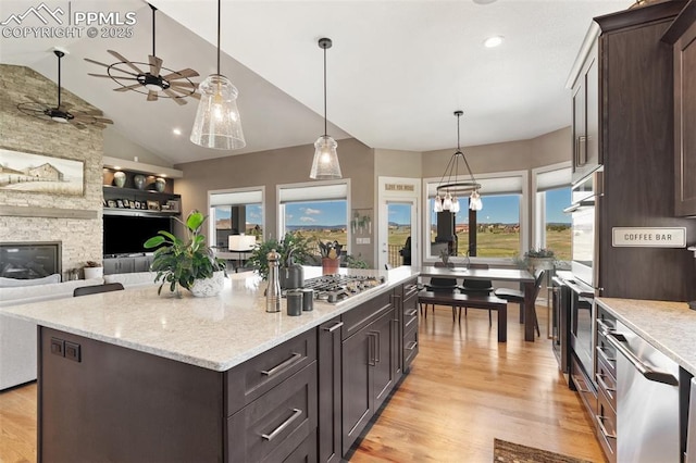 20356 Royal Troon Dr, Monument, CO 80132 - kitchen featuring dark brown cabinets, open floor plan, a ceiling fan, light wood-type flooring, and vaulted ceiling
