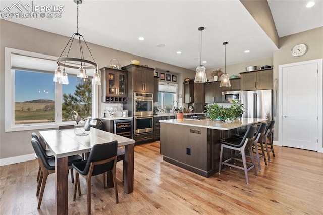 20356 Royal Troon Dr, Monument, CO 80132 - kitchen featuring dark brown cabinetry, appliances with stainless steel finishes, light countertops, beverage cooler, and a center island