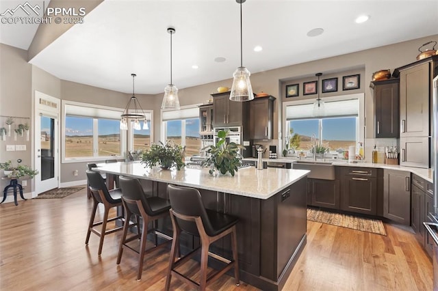 20356 Royal Troon Dr, Monument, CO 80132 - kitchen featuring light wood-style flooring, dark brown cabinets, a sink, a kitchen breakfast bar, and recessed lighting