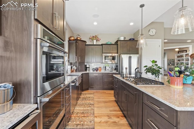20356 Royal Troon Dr, Monument, CO 80132 - kitchen featuring appliances with stainless steel finishes, dark brown cabinetry, a sink, light wood-type flooring, and backsplash