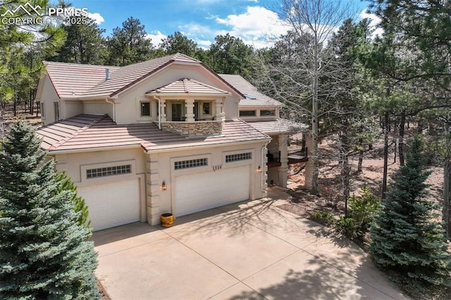 view of front of home featuring a tile roof, stucco siding, a garage, and concrete driveway