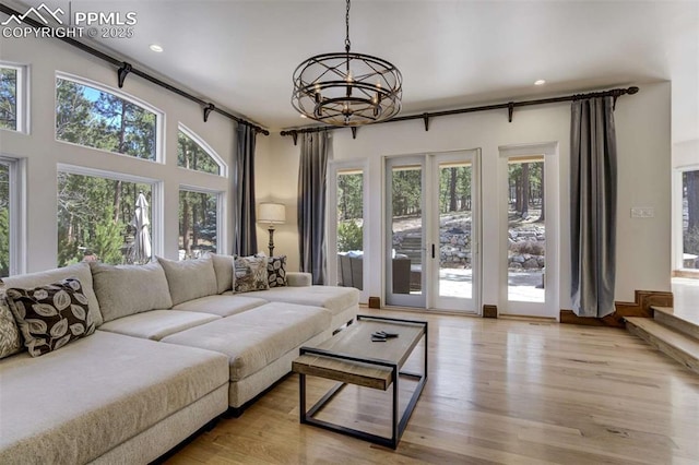 living room with light wood finished floors, a notable chandelier, and a healthy amount of sunlight
