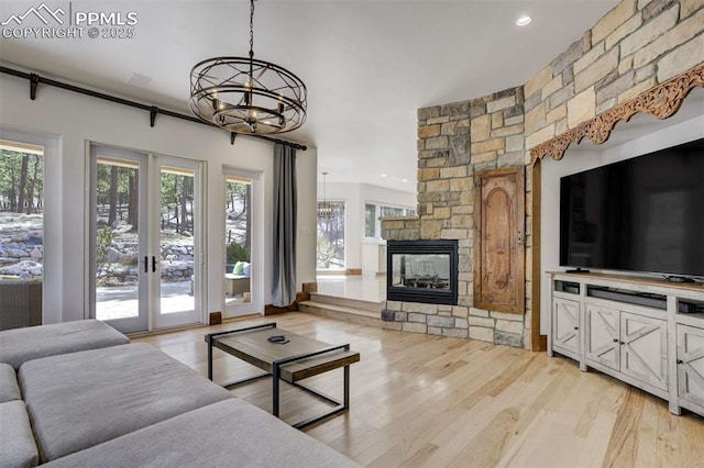 living area with french doors, an inviting chandelier, light wood-style flooring, and a healthy amount of sunlight