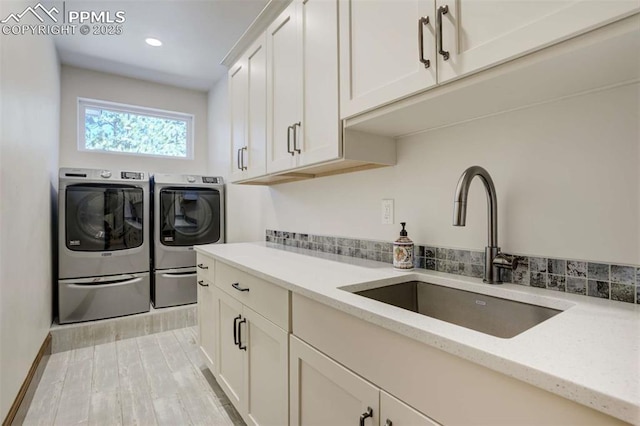 clothes washing area with a sink, light wood-style floors, recessed lighting, cabinet space, and washing machine and dryer