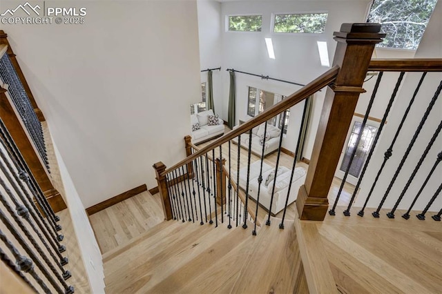 stairway with wood finished floors and plenty of natural light