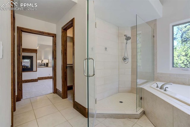 full bath with a shower stall, tile patterned floors, baseboards, and a garden tub