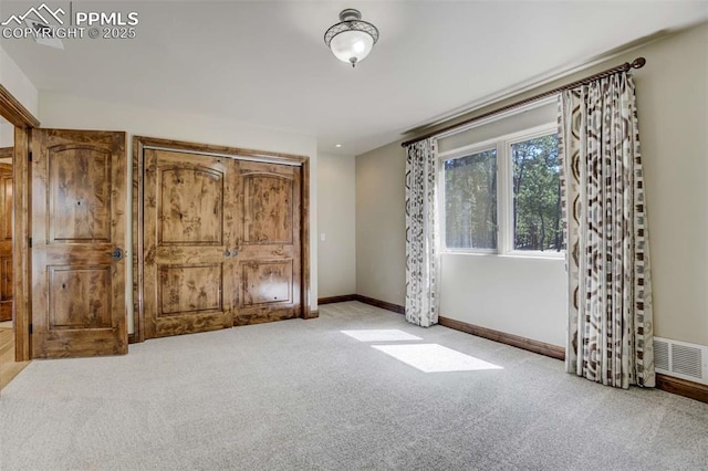 unfurnished bedroom featuring visible vents, baseboards, and carpet flooring