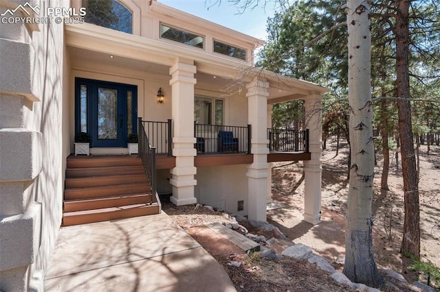 property entrance with a porch and stucco siding
