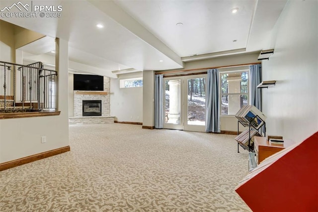 living area with a fireplace, baseboards, carpet, and a wealth of natural light