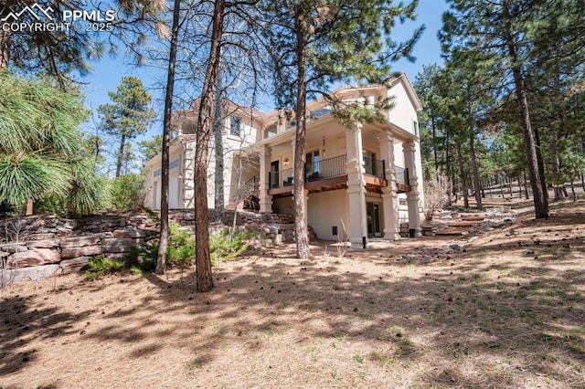 view of side of home with stucco siding and a balcony