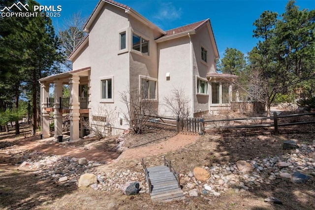 back of house with stucco siding and fence